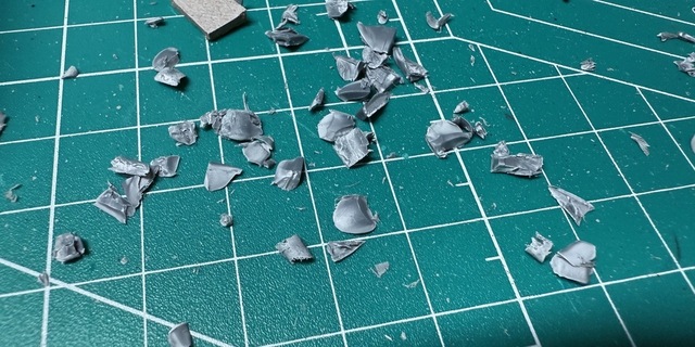 Photograph of a cutting mat covered in chips and shavings of grey plastic