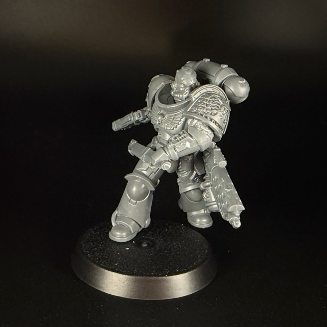 Photo of a space marine miniature in grey plastic, posed lunging towards the camera. The leading shoulder pauldron has been replaced with the Deathwatch pauldron.