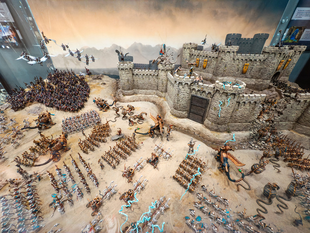 Wide-angle photograph looking down on a large diorama. A huge Tomb Kings army advances from under the camera towards a large castle in the top right of the frame.