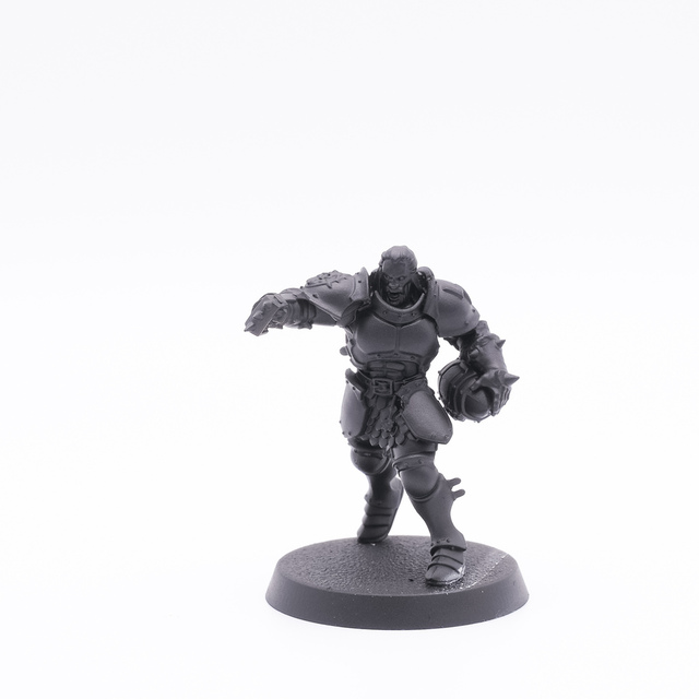 Photo of a converted miniature, primed in black paint. The model is a Stomcast Vindictor, modified to be carrying a Blood Bowl ball in its left hand and with a spiked knuckle-duster in his right