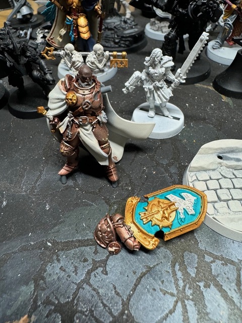 The Valius model during painting again. Now the shield has been painted with gold border and a light blue-green centre. The Stormcast symbol in the middle has been based gold.