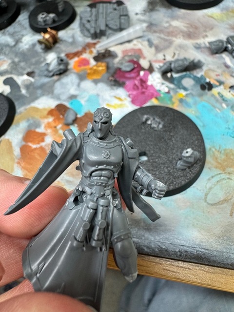 Photograph of a grey plastic Stormcast Eternals miniature, partially built. The left leg has been cut off just above the ankle.