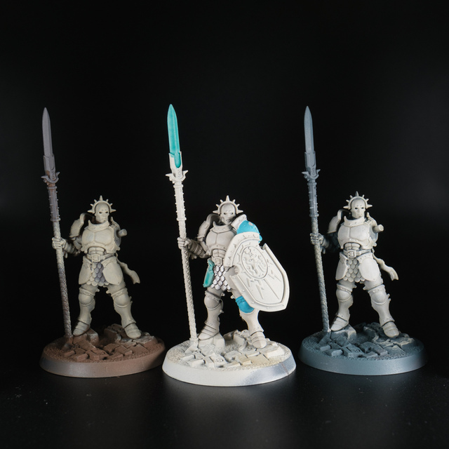 Photograph of three Vindictor models on a black background, sprayed in different undercoat colours — brown, off-white and grey — then each with an off-white base coat that takes on a different hue depending on the undercoat colour: warmer for brown, cooler for grey.