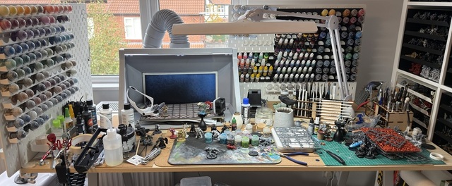 Wide view of my painting table, covered in miniatures, sprues and paint pots.
