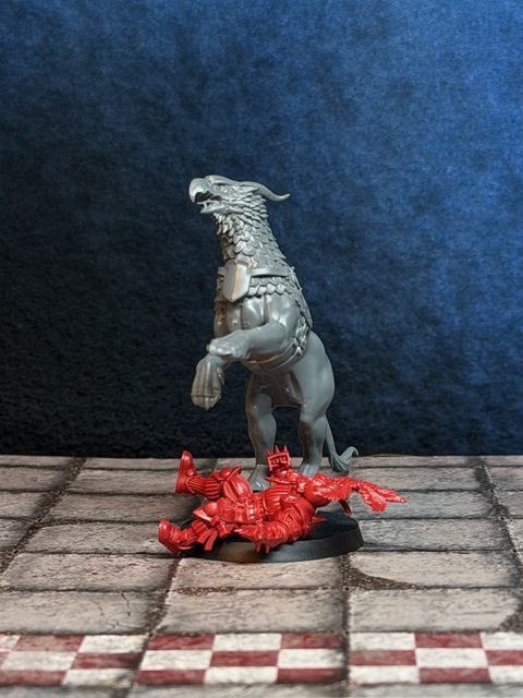 Photo of a gryph-charger model stood up on its hind legs on a 40mm base, rearing over an Imperial Nobility lineman lying prone under its paws