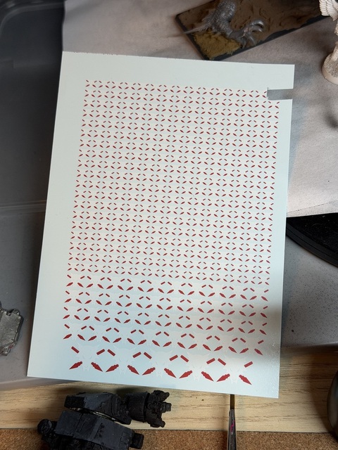 Photo of the transfer sheet. It has tightly-packed rows of small Wolfspear icons, a few rows of larger icons and then a final row of 5 large icons. One smaller logo has been cut out towards the top right