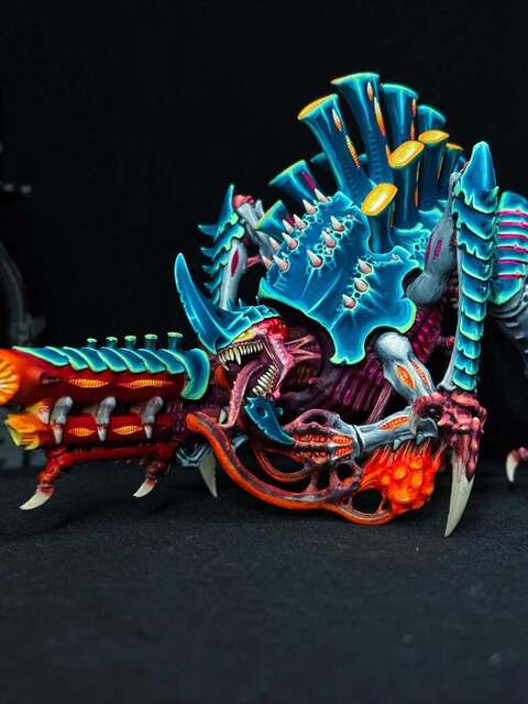 Photograph of a Tyrannofex painted in a blue and orange scheme with high contrast neon edge highlights, creating something of a synthwave/cyberpunk colour scheme