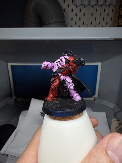 Photo of a space marine miniature painted in quarters, with diagonally opposing quarters painted either red or pink