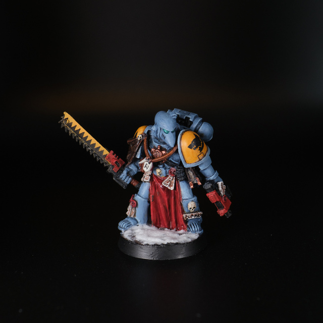 Photograph of a painted space marine in mark 6 armour, with a chainsword and bolt pistol. The miniature is painted as a Space Wolf, with black-and-yellow 'teeth' design down the chainsword