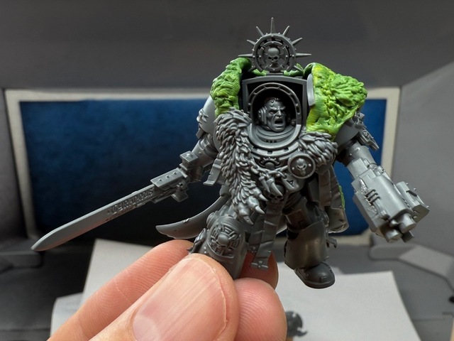 Close-up photo of a terminator captain model with green stuff-moulded fur over its shoulders, connected to a standard plastic fur/pelt part around the neck and chest. The green stuff has some visible fingerprints and smudging