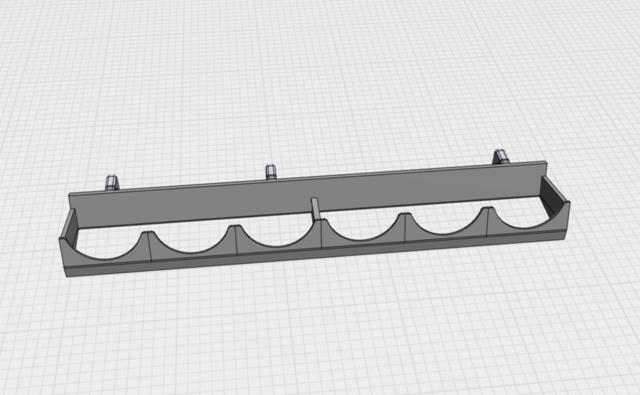 Screenshot of a 3D model on a square-ruled background. The model is of a simple horizontal frame, with half-circle cutouts on the front bar for round paint pots to balance on and a flat board at the back, angled up slightly so the paint pots can sit against it