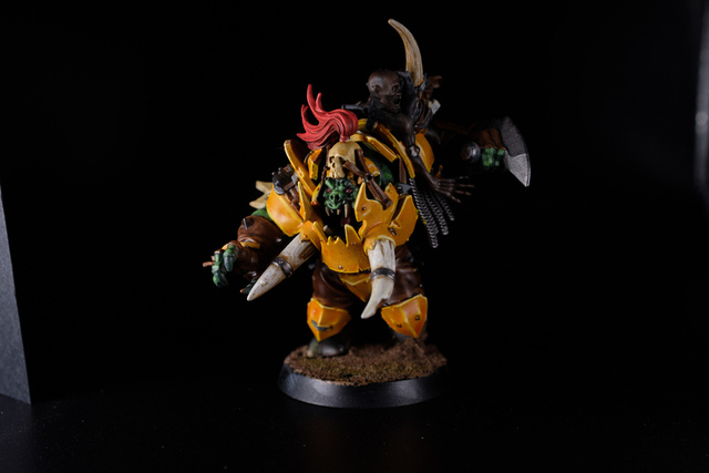 Photo on a black background of a mostly-painted Varag Ghoul-chewer model. The armour is painted a deep orange-yellow with highlighting.